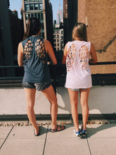 Load image into Gallery viewer, Two girls wearing laser cut angel wing shirts, in pink and grey, with a view of the Empire State Building. 