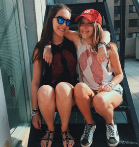 Two of our models wearing our red wings. One of them wearing a tank top with black tank top with red wings and the other wearing a white tank top with red rings. 