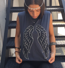 Load image into Gallery viewer, Photo of girl sitting on steps. She is wearing a grey tank with silver and black angel wings, while she is looking down at the tank.